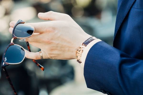 shallow focus photography of man holding sunglasses