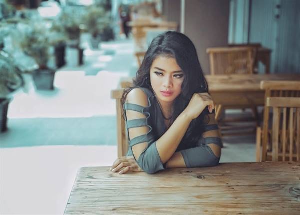 woman in gray long-sleeved top sitting on chair near green leafed plant during daytime