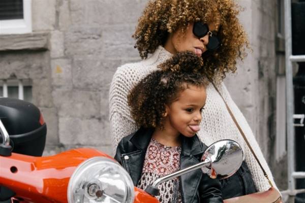 woman and girl showing their tongues beside motorcycle